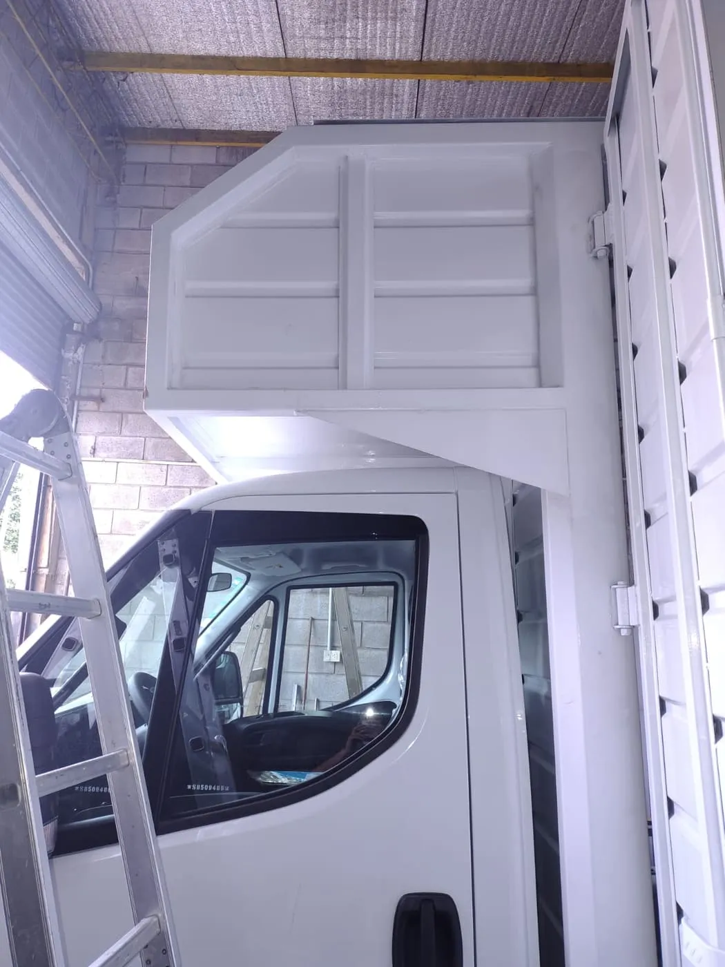 Furgón blanco con deflector aerodinámico sobre cabina montado en taller