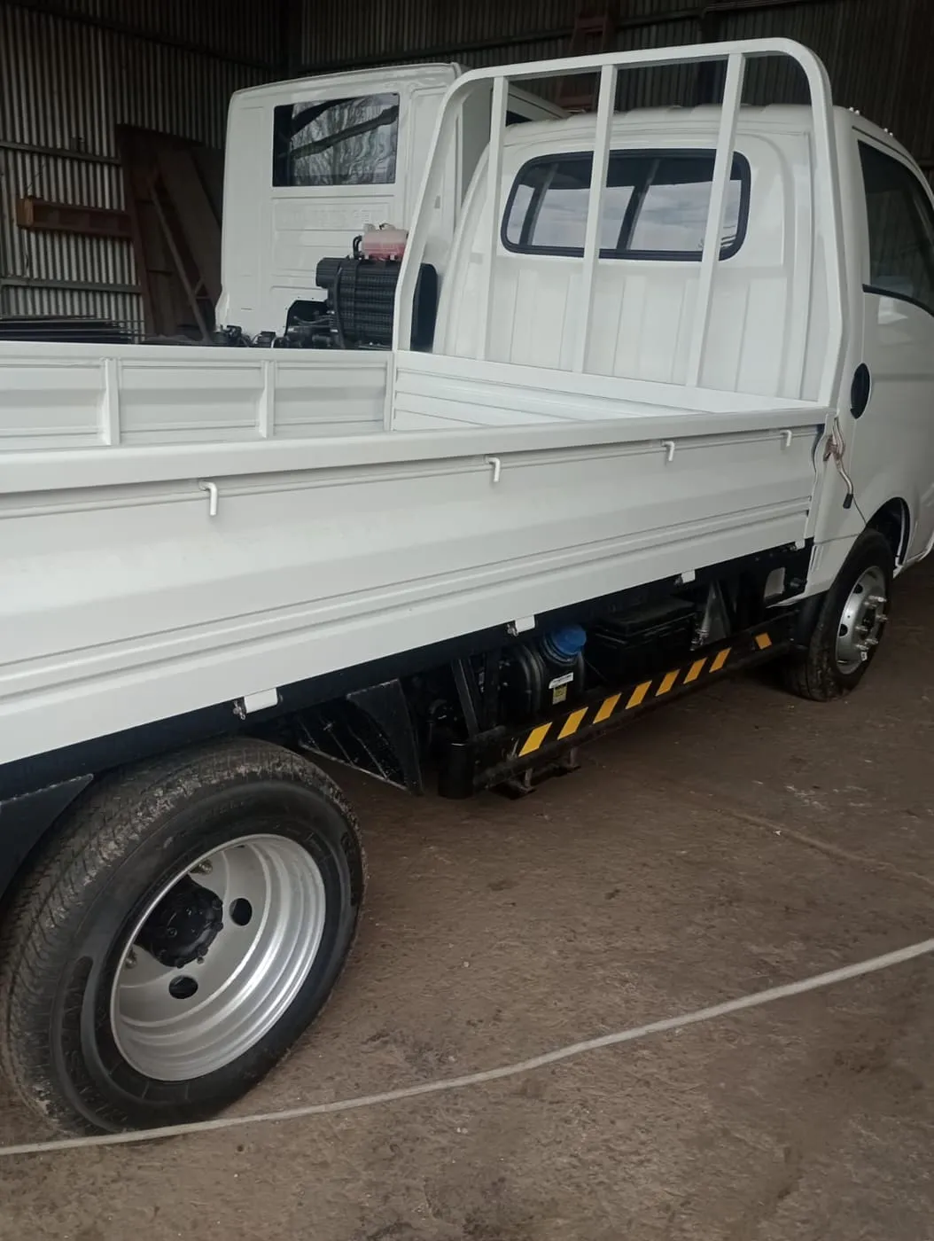 Utilitario de carga con caja de estacas y baranda antiproyección terminada en blanco